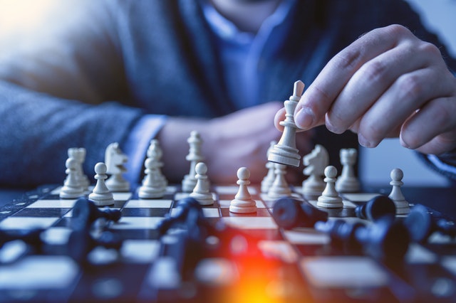 person holding white king over chessboard