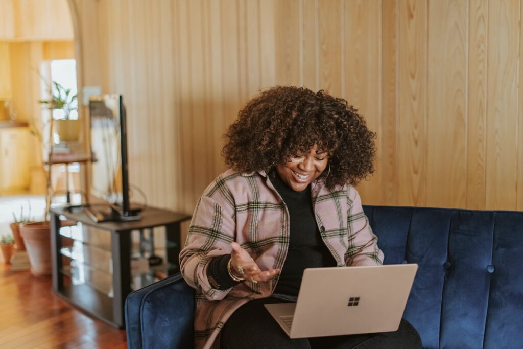 woman smiling and gesturing while looking at laptop