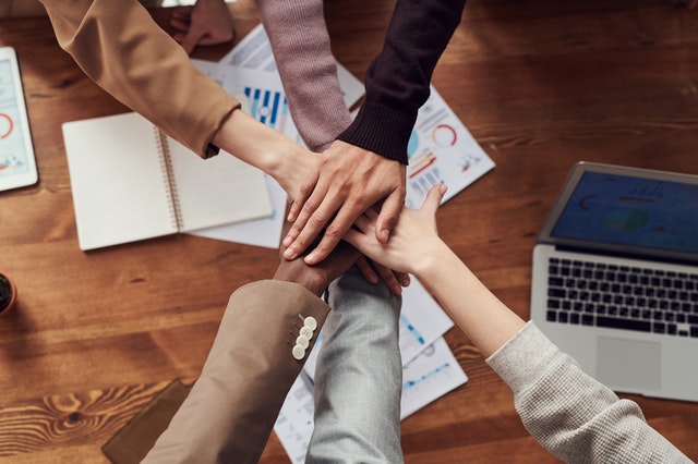 team members stacking hands over table