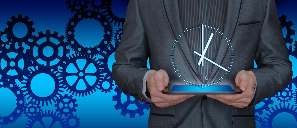 person holding tablet computer with clock image overlay and gears in background - time & work concept image